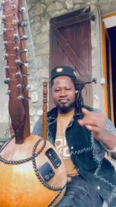 Sako Wana, artiste malien, joue de la kora devant une façade en pierre lors de la promotion de Sagaly 2026 à Villeurbanne, le 17 octobre 2026